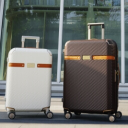 Two luggages on the ground, smaller white on the left, bigger brown on the right